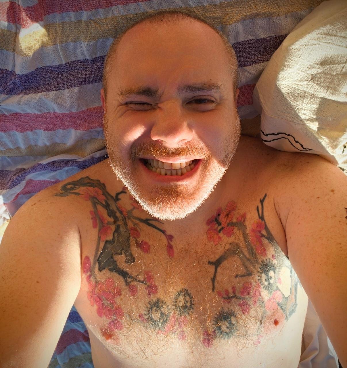 un selfie depuis la serviette de plage avec un sourire crispé et ébloui