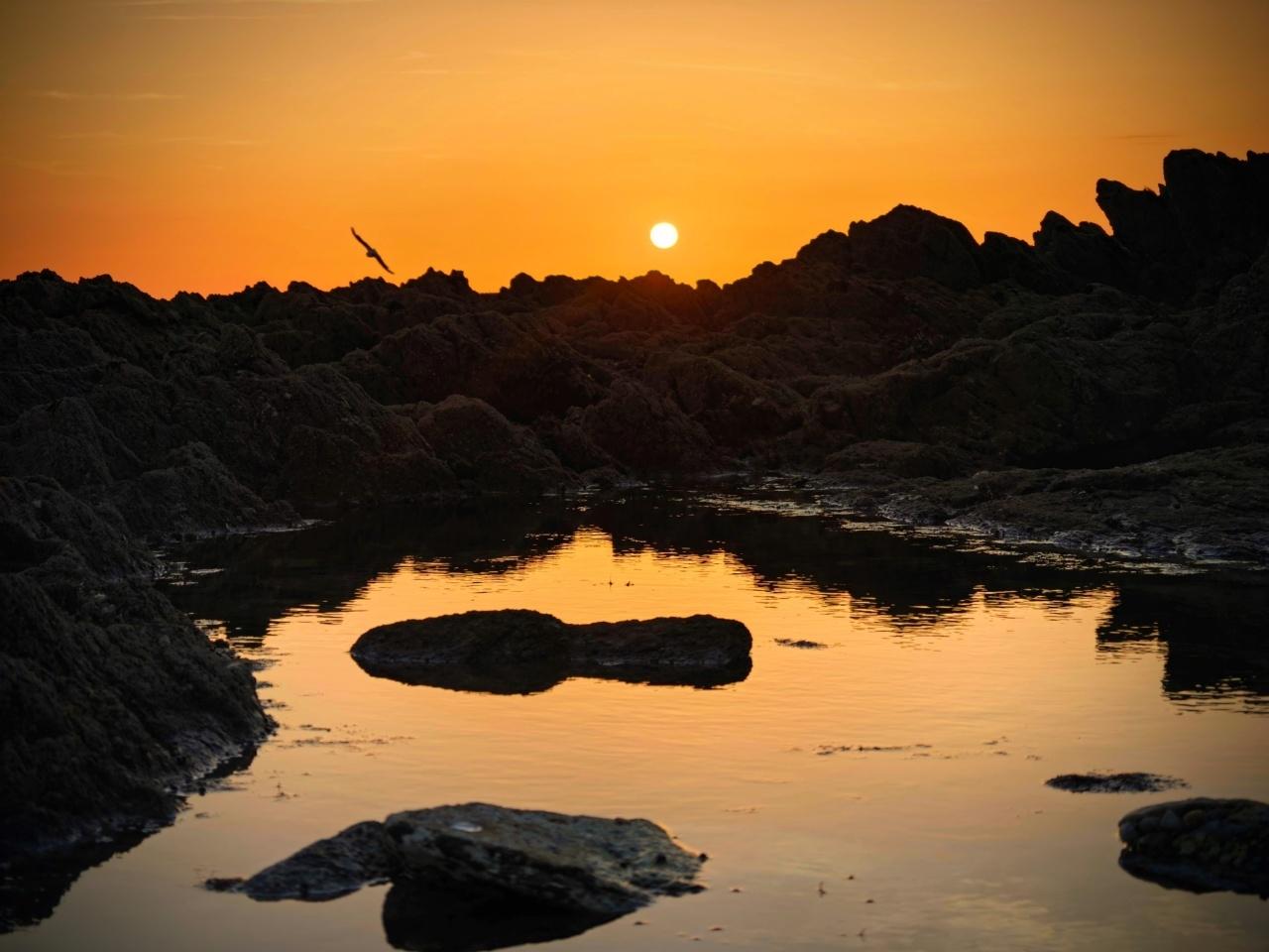 Coucher de soleil sur le bord de l'océan vu depuis une grosse flaque d'eau de mer